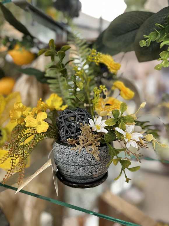 Small floral arrangement with yellow and white flowers in a gray pot