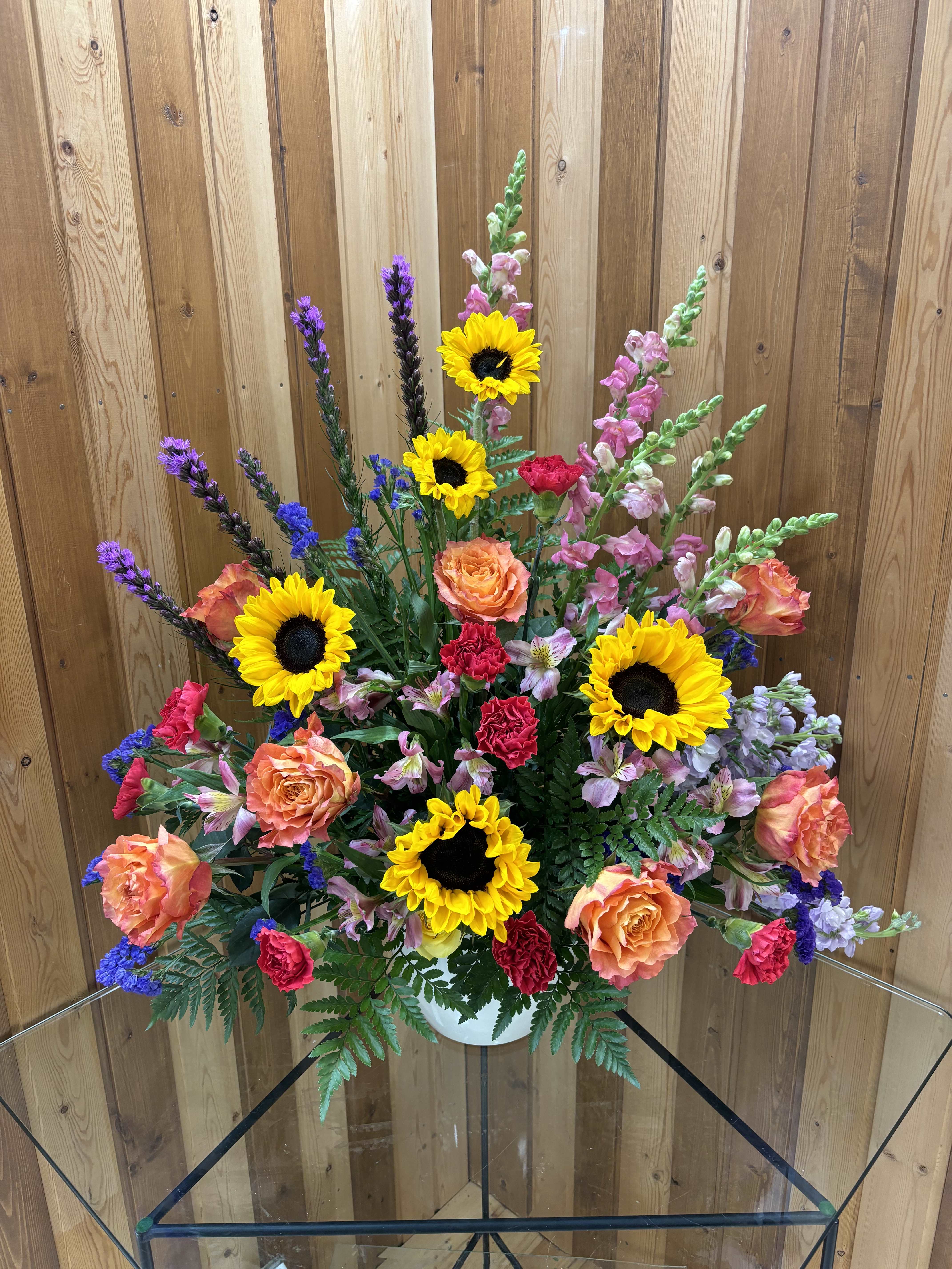 Mixed bouquet with sunflowers, roses, and snapdragons in a white vase