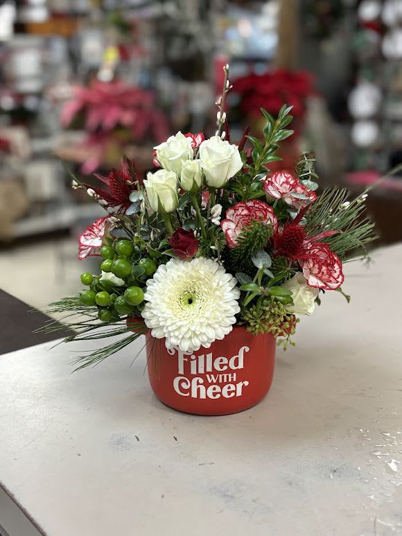 Mixed floral arrangement in a red container with white and red blooms