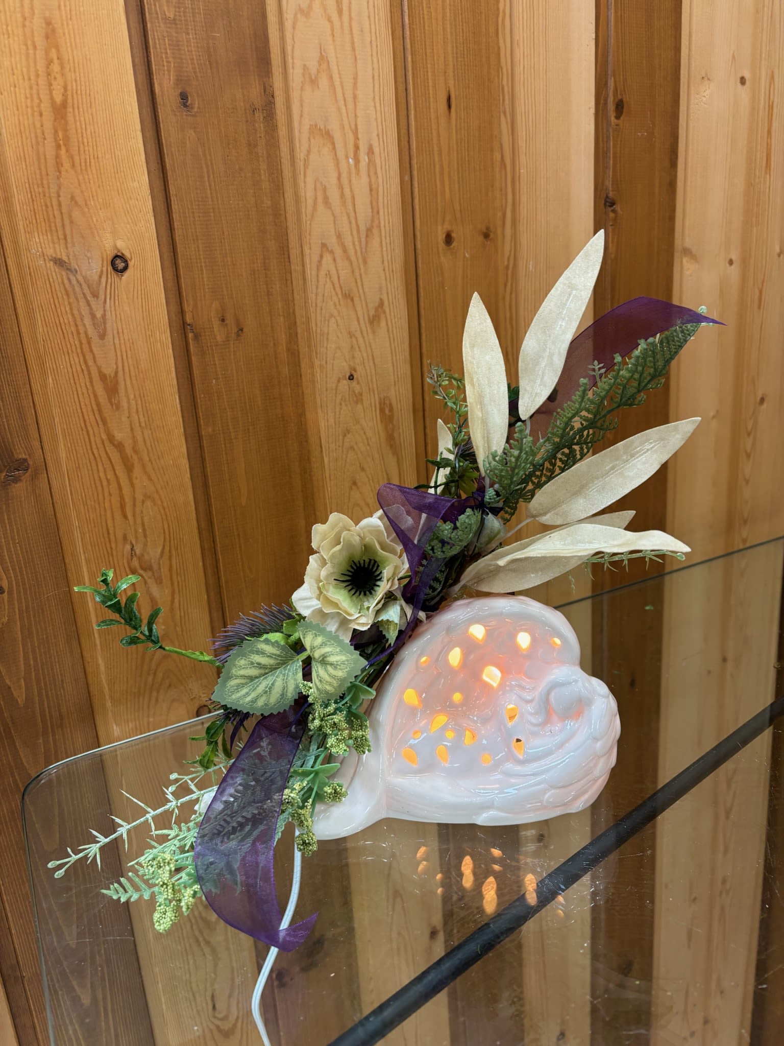 Decorative ceramic snail with a floral accent and purple ribbon