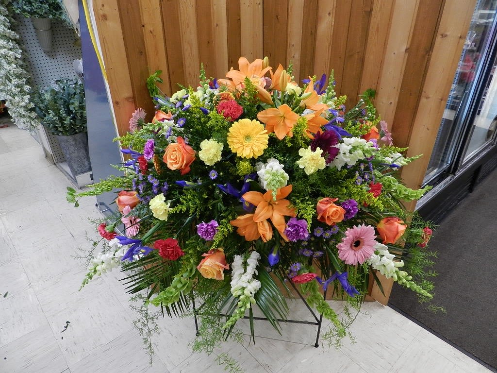 Large mixed floral spray with orange lilies, roses, and gerbera daisies