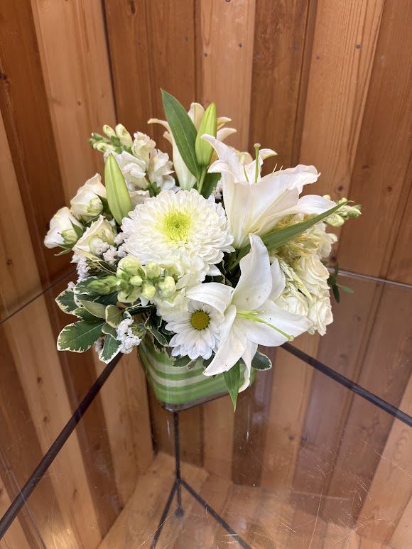 White lilies and chrysanthemums in a green striped vase