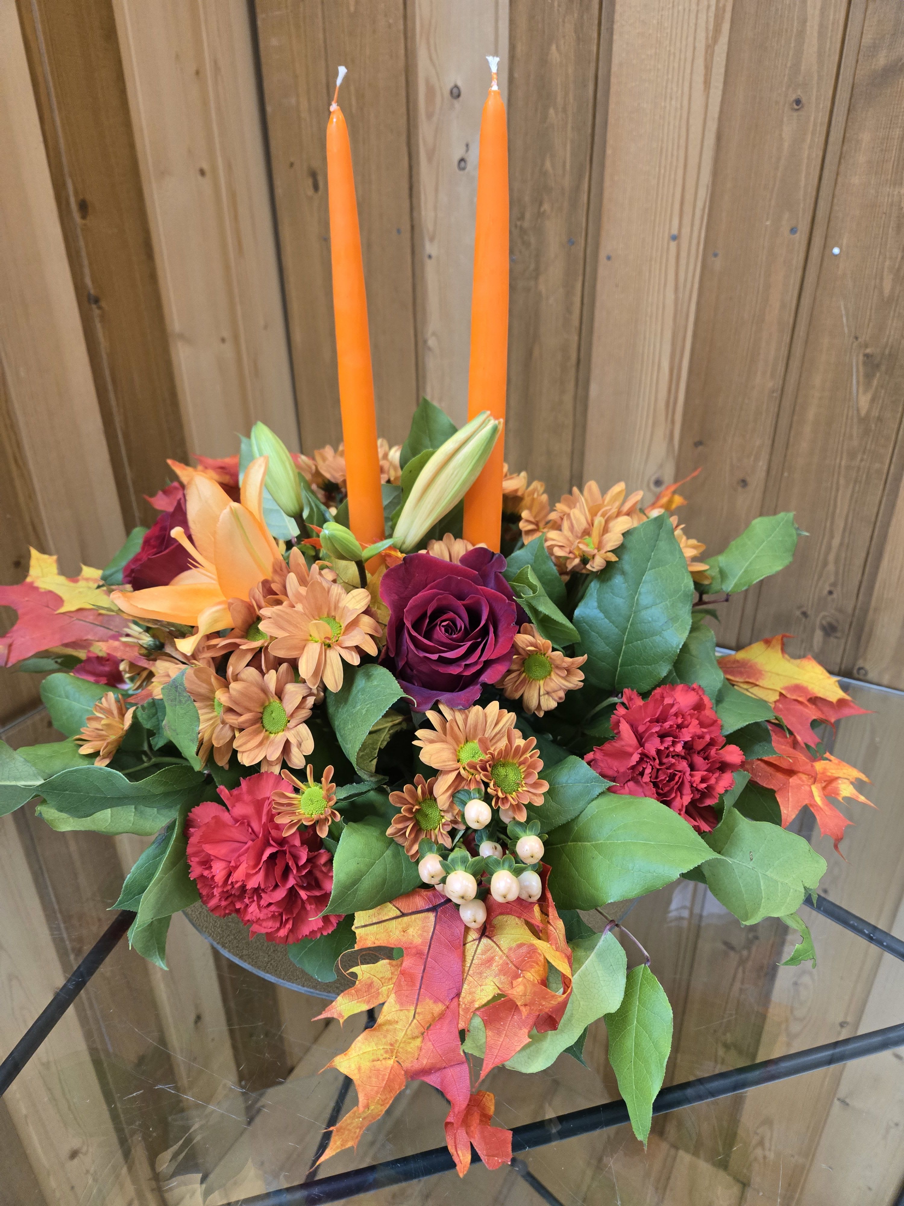 Autumn floral centerpiece with orange candles in a low glass bowl