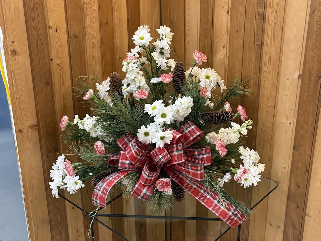 Christmas floral arrangement with white daisies, pink carnations, pinecones, and a red plaid bow