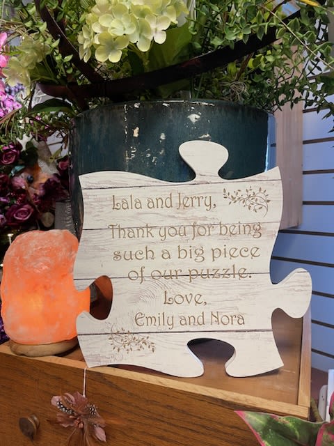 Puzzle-shaped thank-you sign beside flowers and a salt lamp