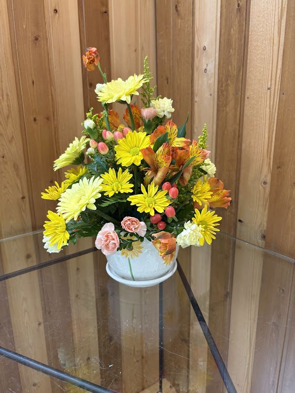 Summer Sun Bouquet - Bright, sunlit blooms of yellow, orange, peach, and soft pink combine in a joyful summer arrangement that says "you brighten my day." The Summer Sun Bouquet is a cheerful flower arrangement perfect for Mother's Day, birthdays, get well wishes, housewarming, or simply a Just Because surprise - and it also reads fresh for Easter or any spring-summer celebration. She'll feel genuinely seen when this compact, rounded design arrives on her table, radiating warmth and optimism.  This arrangement mixes yellow daisy-style chrysanthemums, peach and cream carnations, sunlit gerbera-style daisies, orange-yellow alstroemeria, and other seasonal blooms, with small clusters of pink berries for playful texture. The flowers are gathered tightly in a clean white ceramic pot for a casual, modern look that fits countertops, desks, or bedside tables. Dimensions are compact for easy placement; substitutions may be made with flowers of equal value and color if any variety is unavailable, keeping the same sunny palette and overall presentation.  Order from Haehn Florist, Greenhouses, &amp; Flower Delivery at 410 Hamilton Rd. Wapakoneta. Follow us on Facebook at www.facebook.com/haehnflorist for seasonal updates and delivery info. Care tip: refresh the water every couple of days and keep away from direct heat to extend vase life.