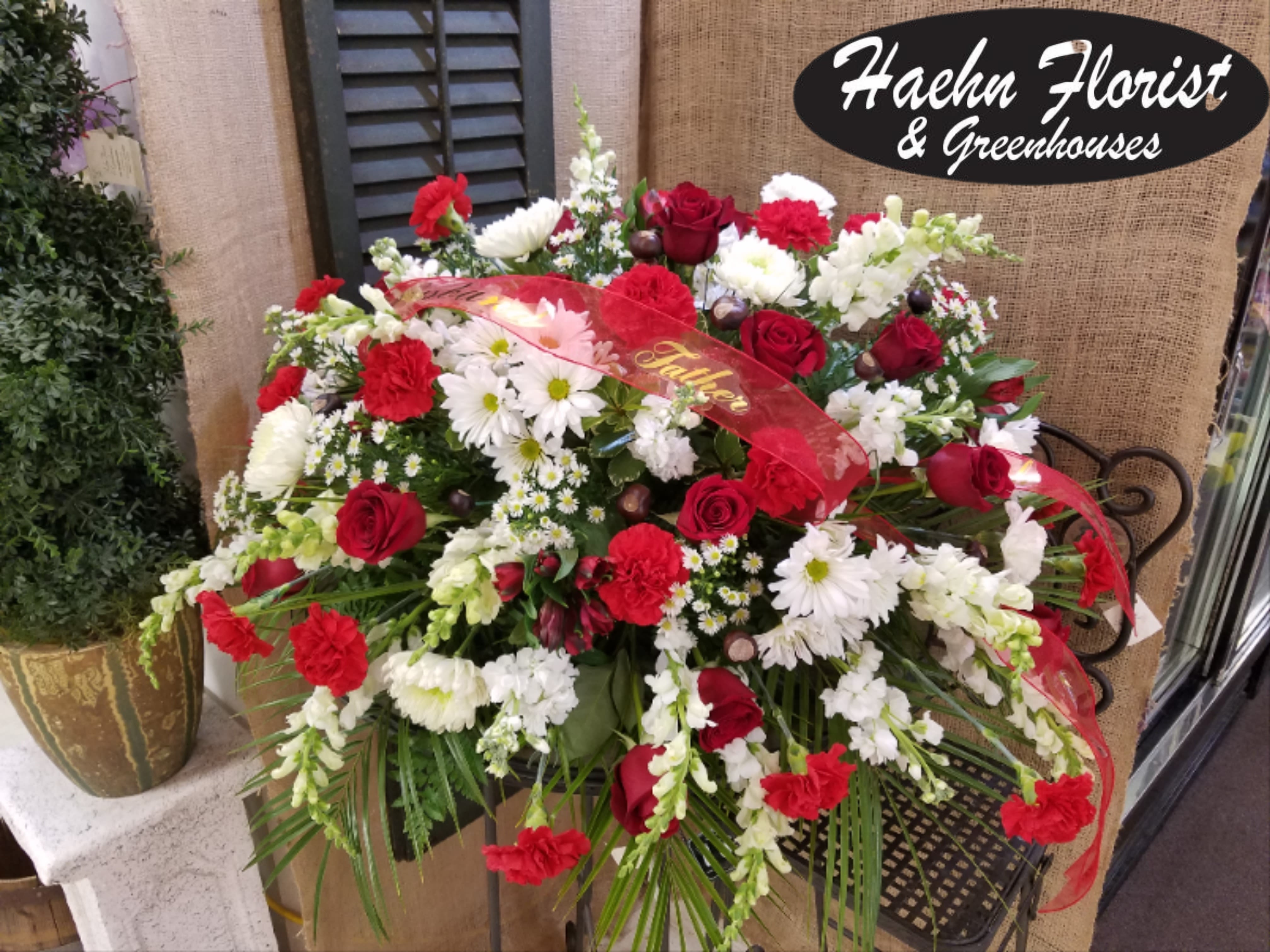 Red and white floral arrangement with roses and daisies in a basket