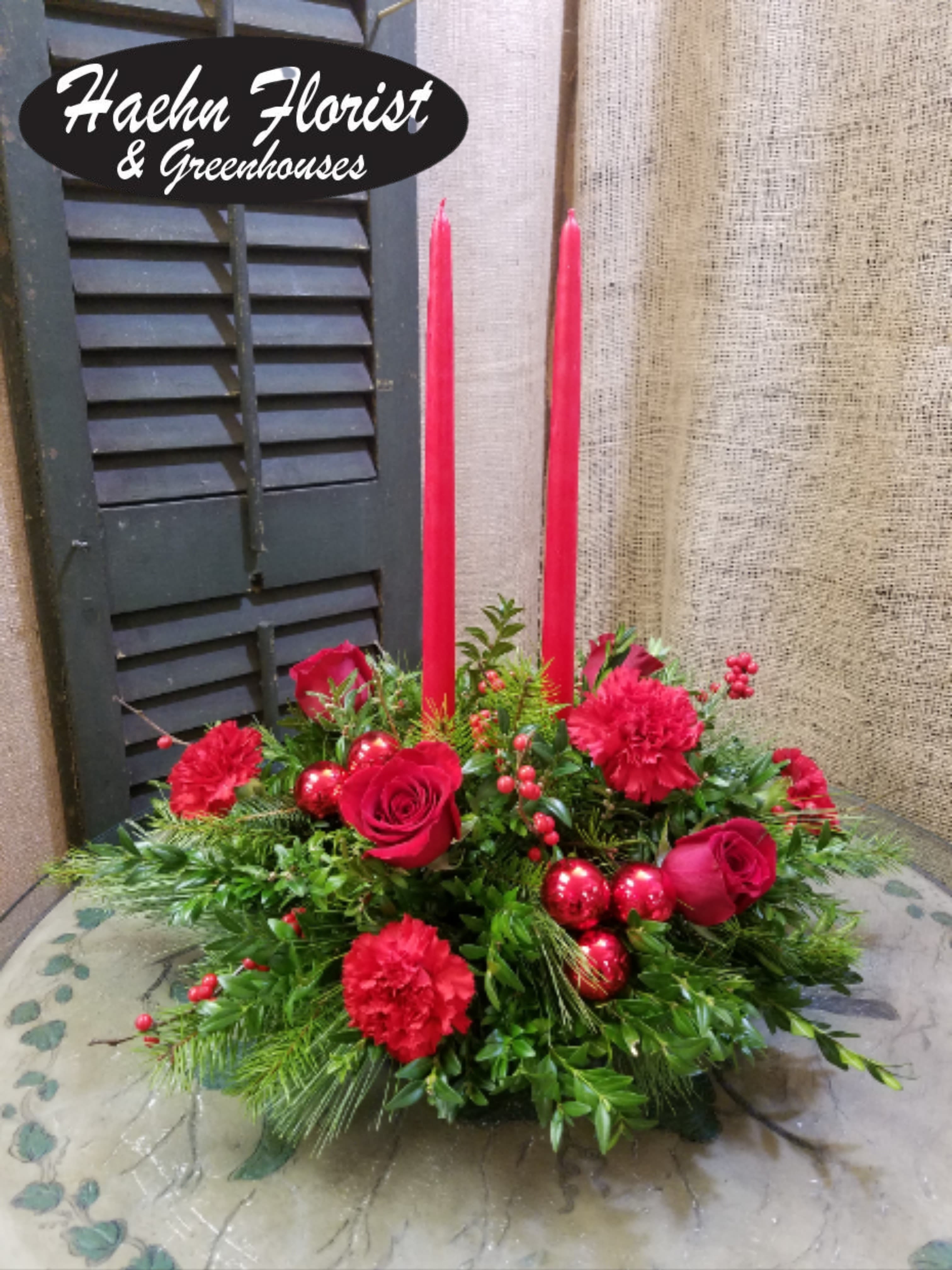 Red roses and carnations with tall red candles in a low arrangement
