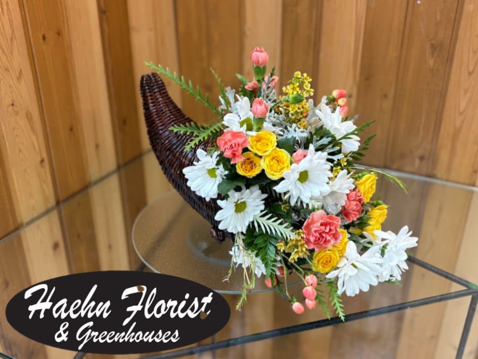 Mixed bouquet in a woven horn-shaped basket with white daisies and pink and yellow flowers