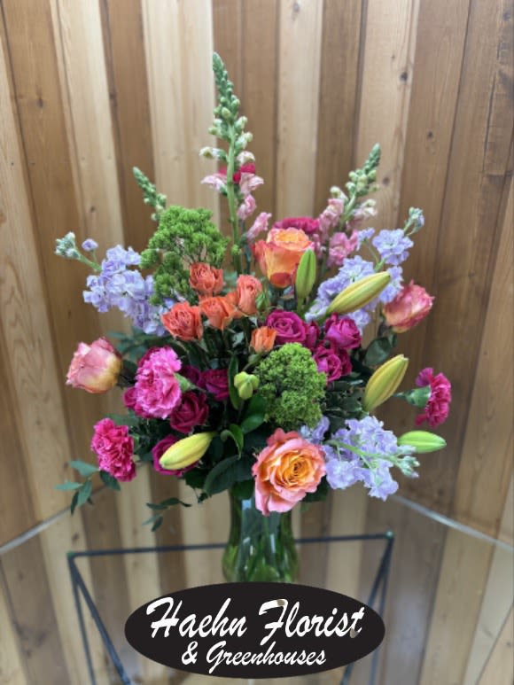 Tall mixed bouquet in a glass vase with pink, orange, and lavender flowers