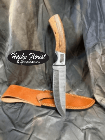 Hunting knife with a leather sheath on dark fabric