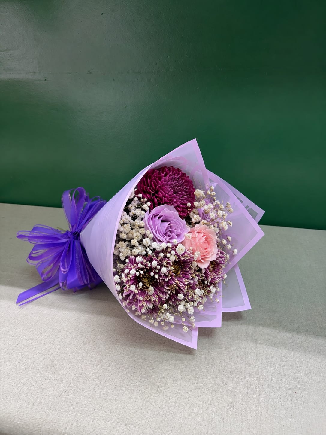 Bouquet of purple, pink, and white flowers wrapped in lavender paper