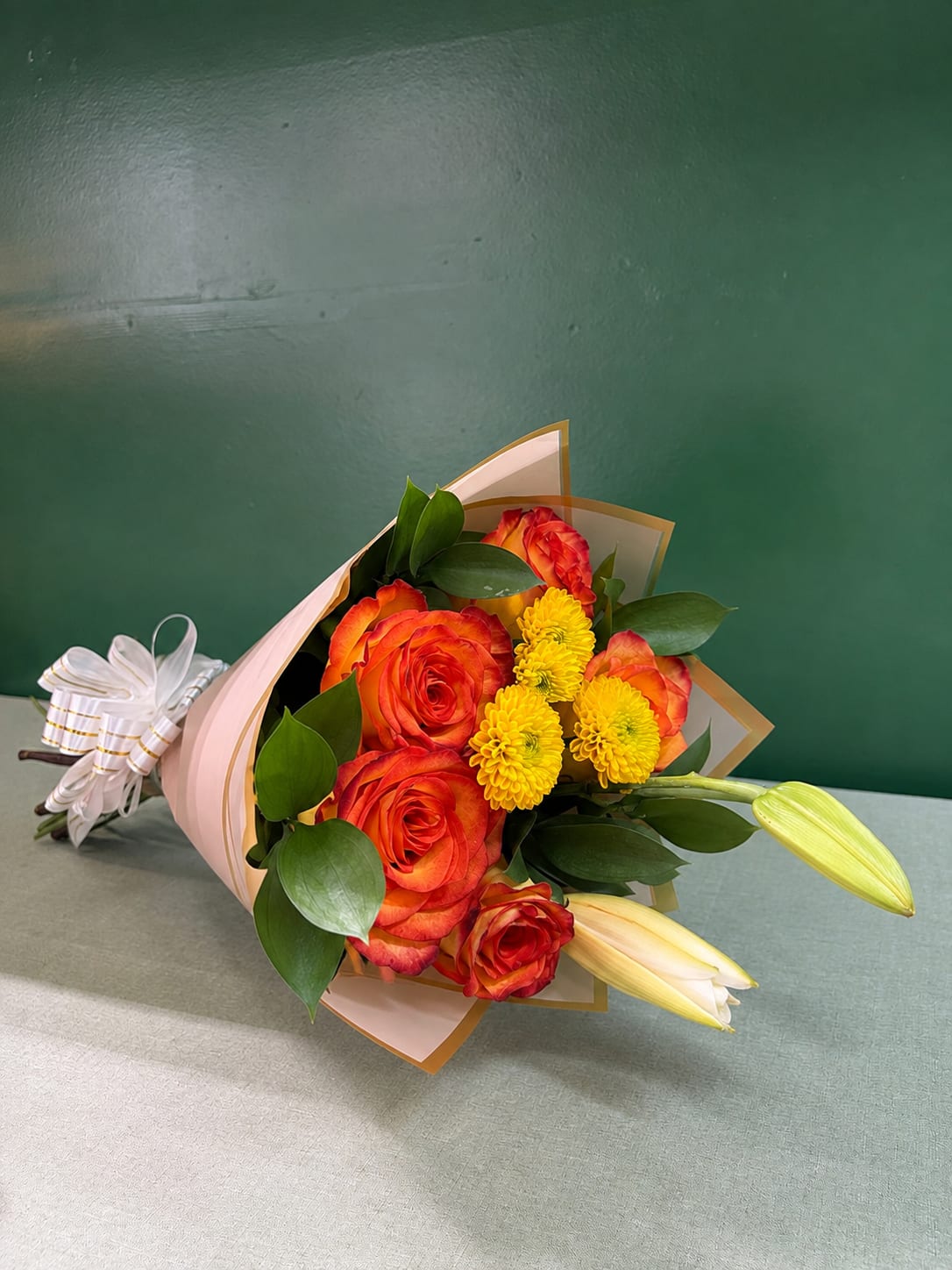 Bouquet of orange roses and yellow mums wrapped in pink paper