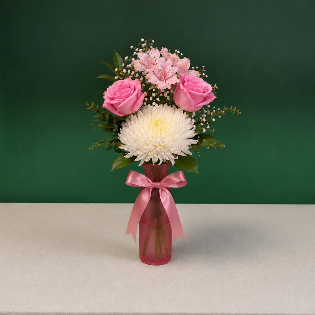 Pink roses and white chrysanthemum in a pink vase with a ribbon