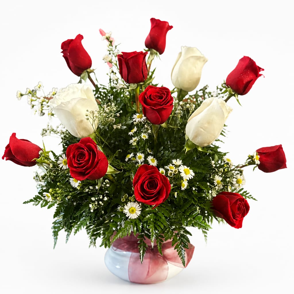 Red and white roses arranged in a round vase with small white daisies