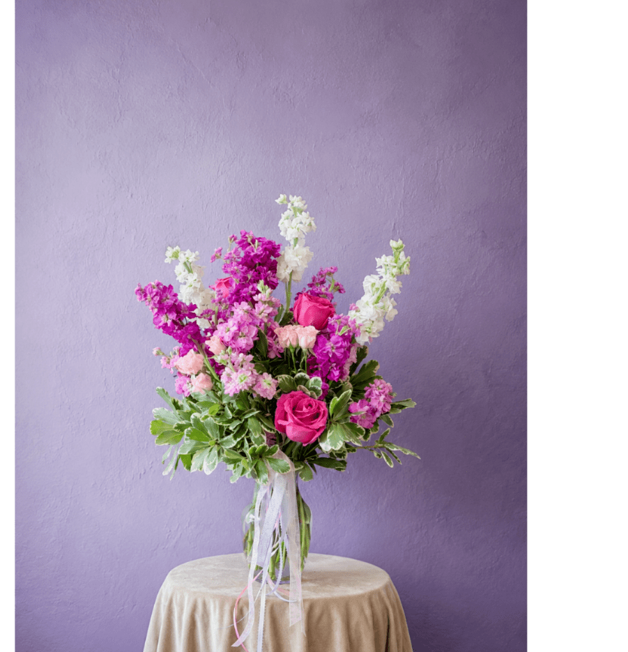 Pink and white flower arrangement in a clear glass vase on a draped table