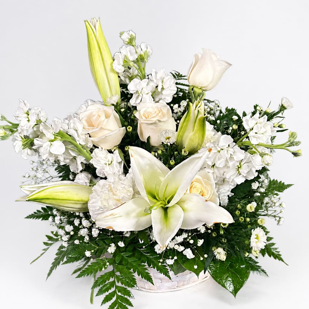 White lilies and roses arranged in a white basket