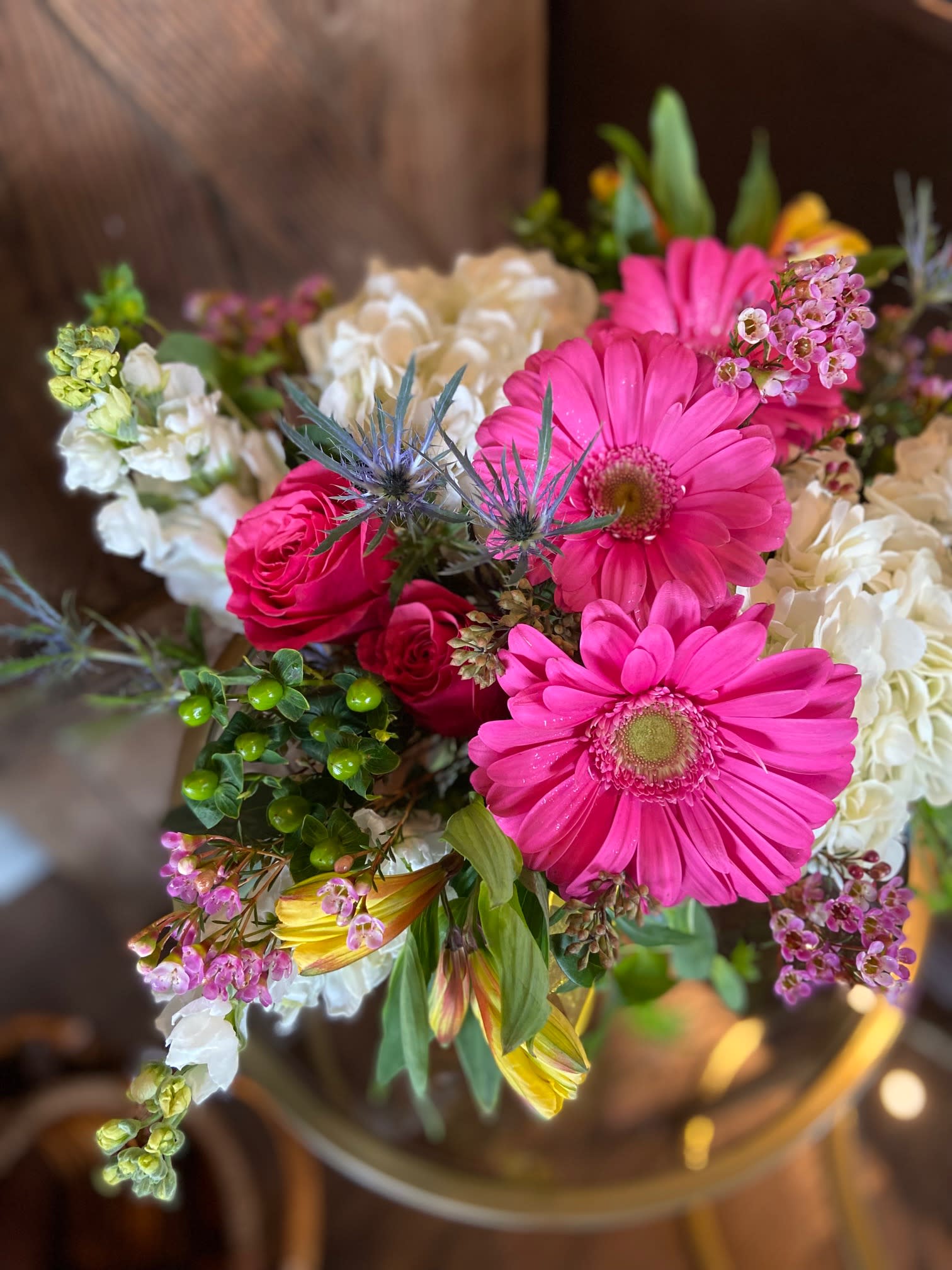 Mixed bouquet with bright pink gerbera daisies, roses, and white blooms in a clear vase