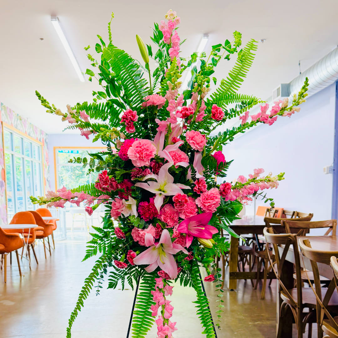Tall pink floral arrangement with lilies and carnations on a stand