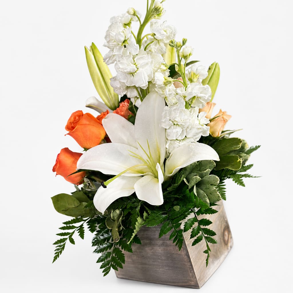 White lilies and orange roses in a wooden vase