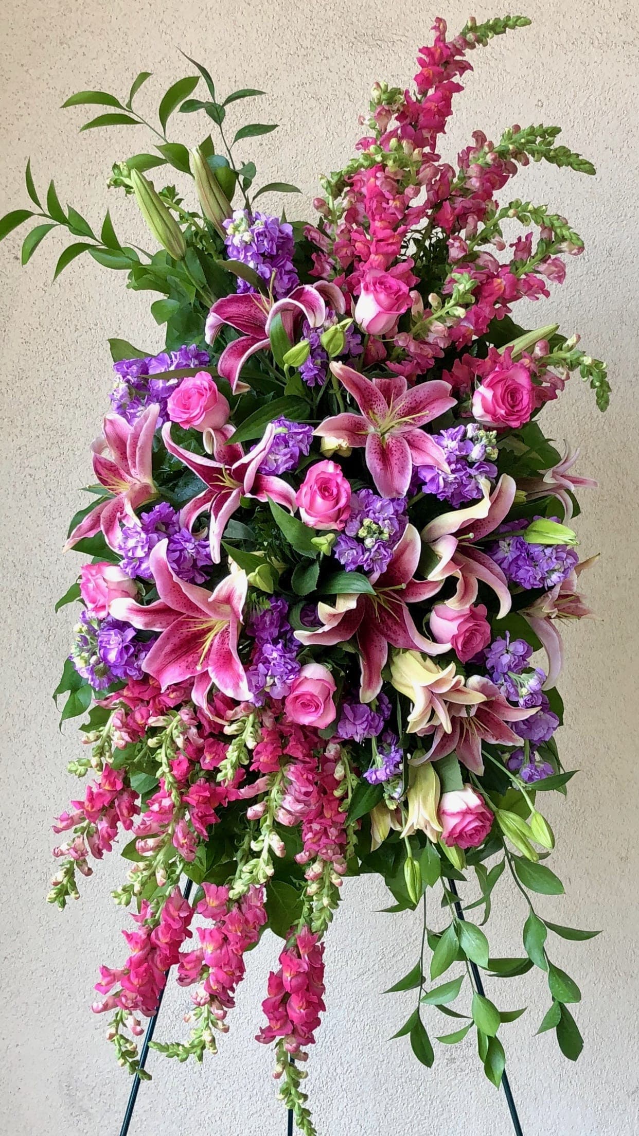 Tall standing floral spray with pink lilies, roses, and purple blooms