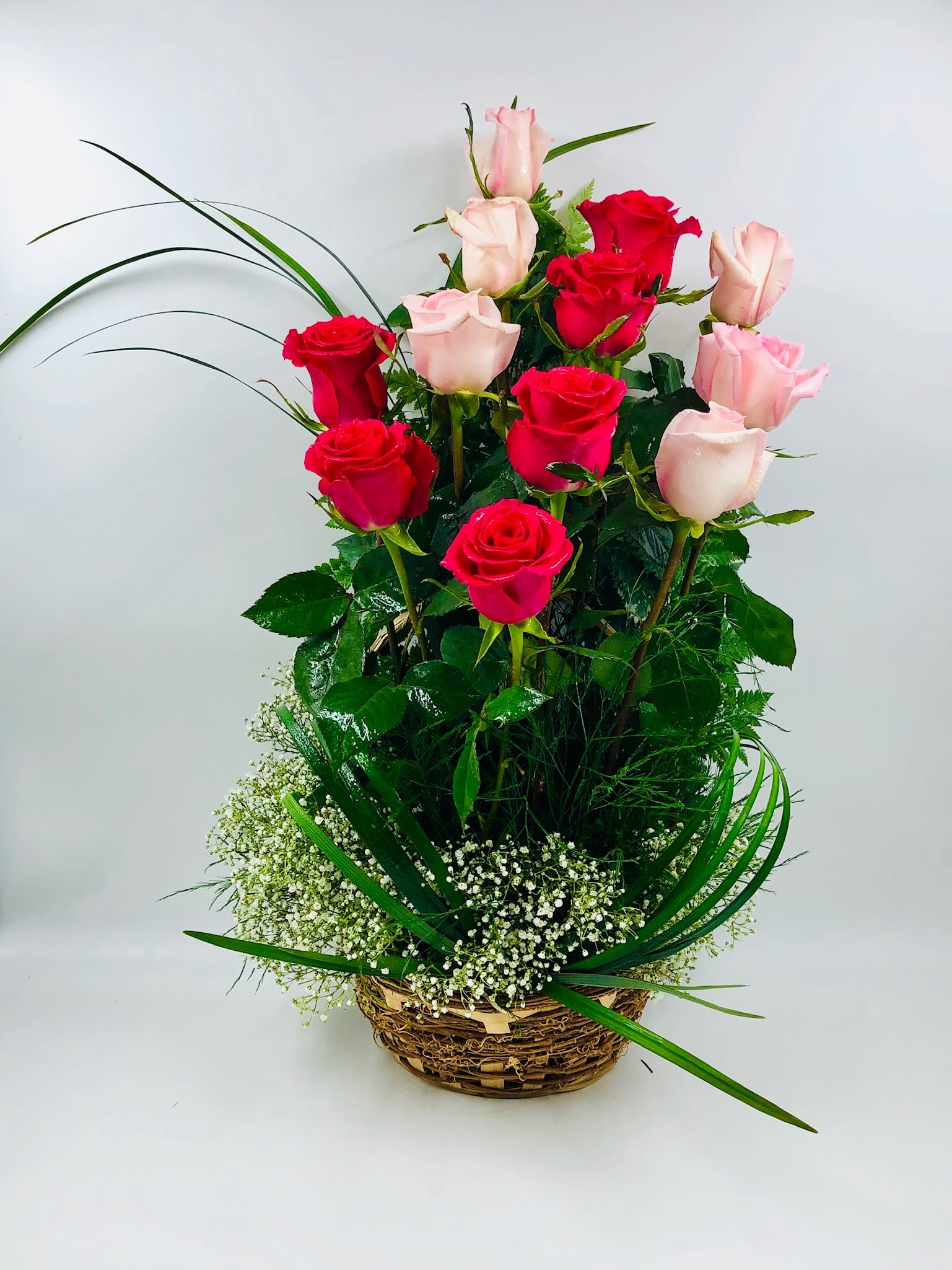 Basket arrangement of red and pale pink roses with baby's breath