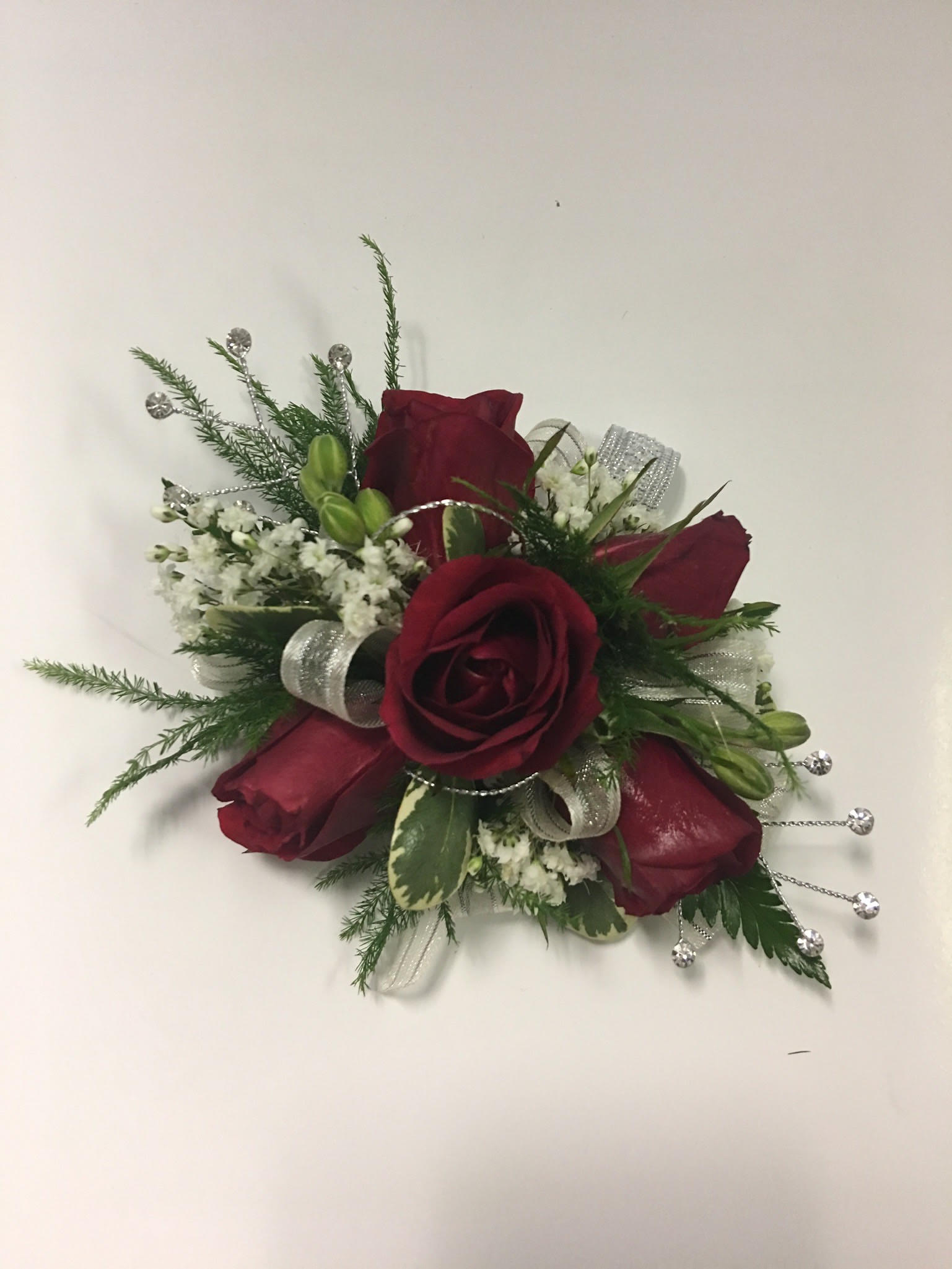 Red rose corsage with white filler and silver ribbon