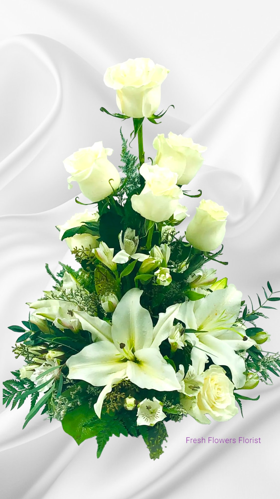 White roses and lilies in a tiered floral arrangement