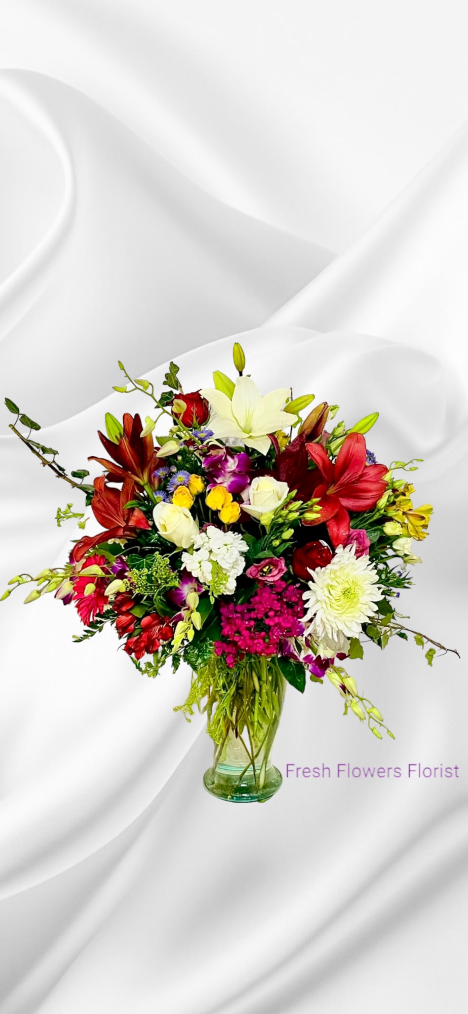 Mixed bouquet of lilies, roses, and daisies in a glass vase