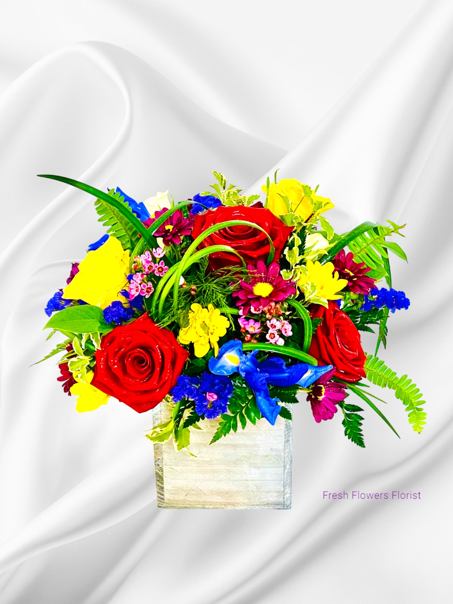 Bright mixed bouquet of roses and daisies in a square vase