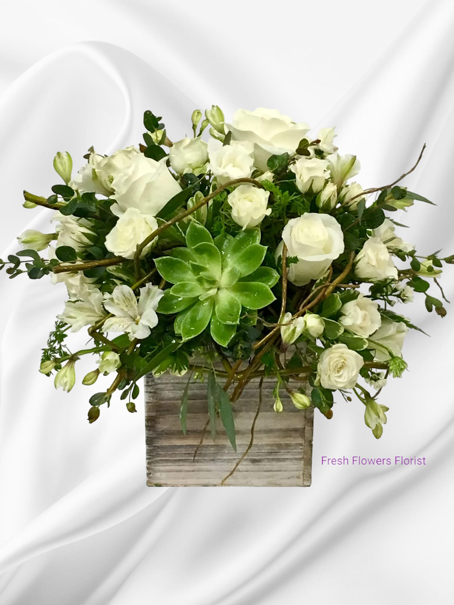 White roses and alstroemeria in a rustic square vase with a green succulent