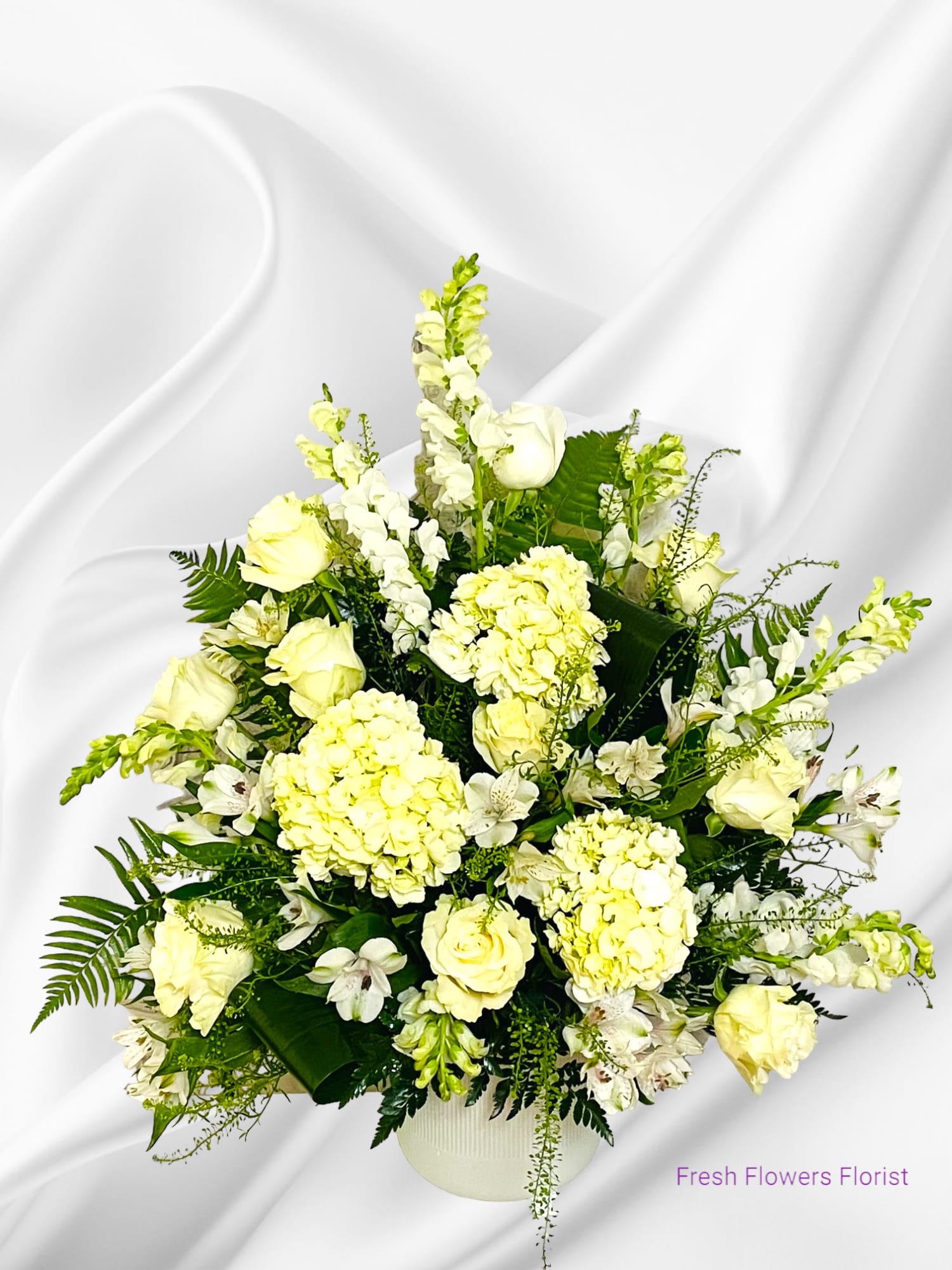 White floral arrangement in a round vase with roses and hydrangeas