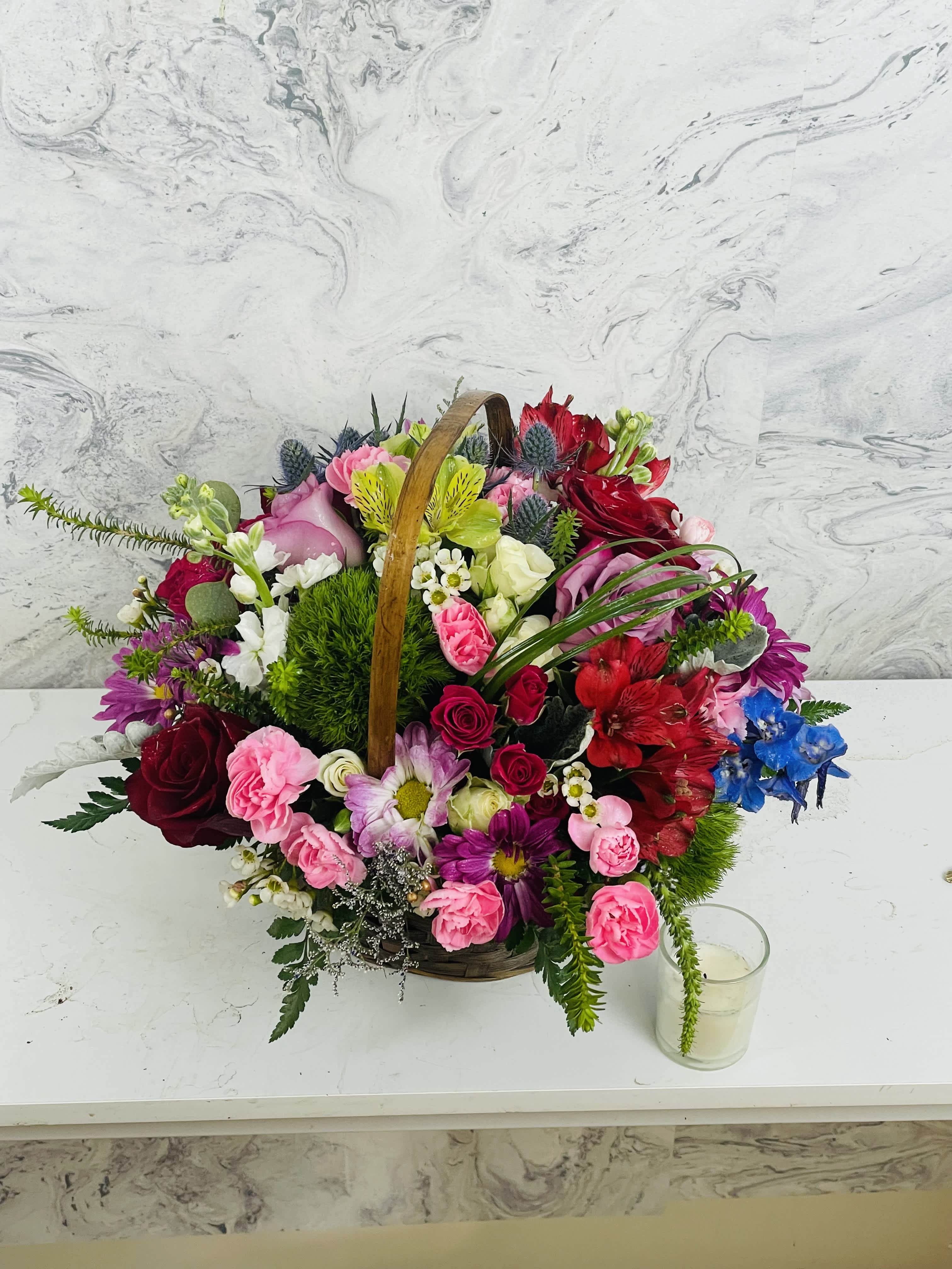 Basket arrangement of mixed pink, red, white, and blue flowers