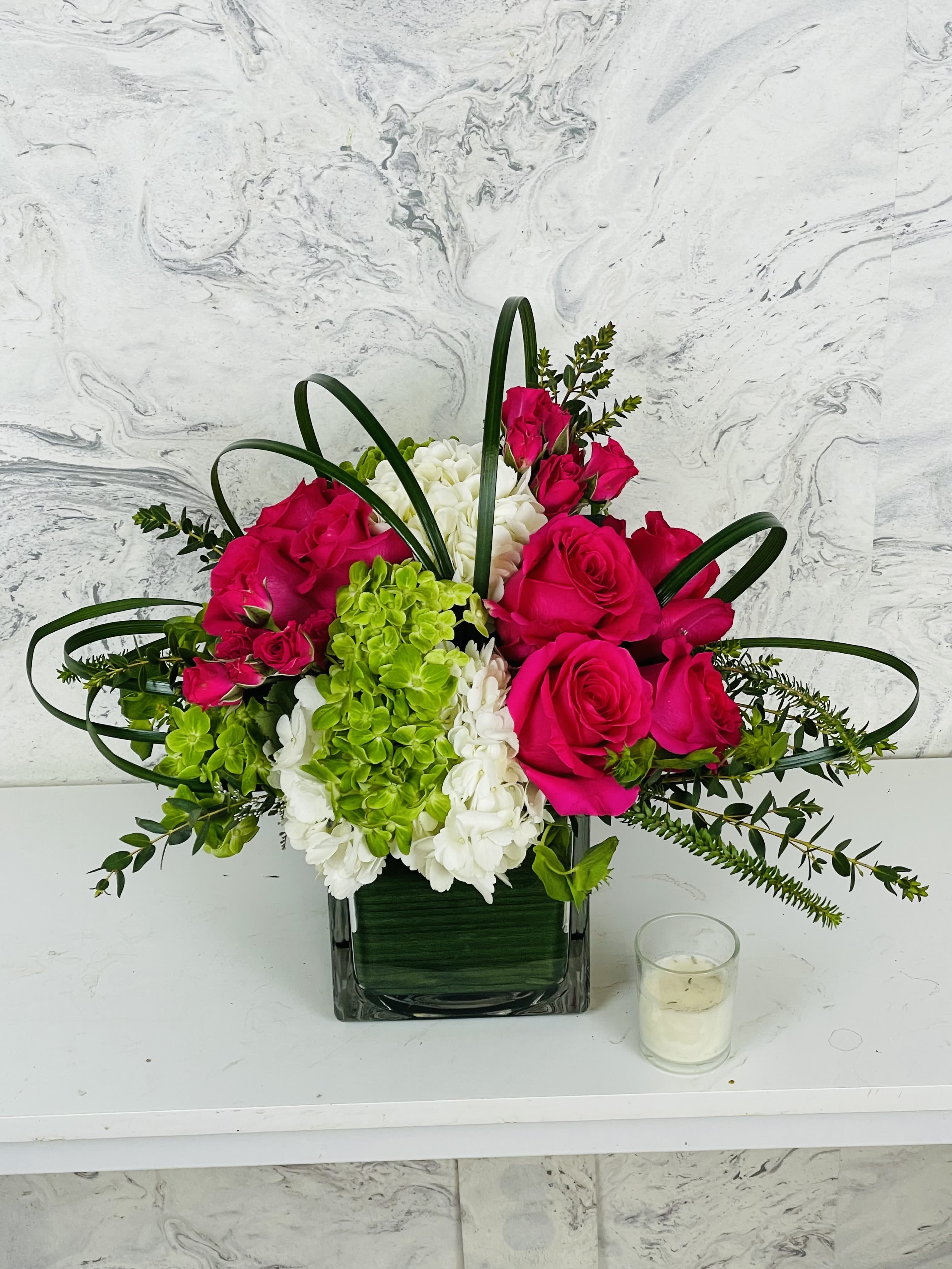 Pink roses and green-white hydrangeas in a square glass vase