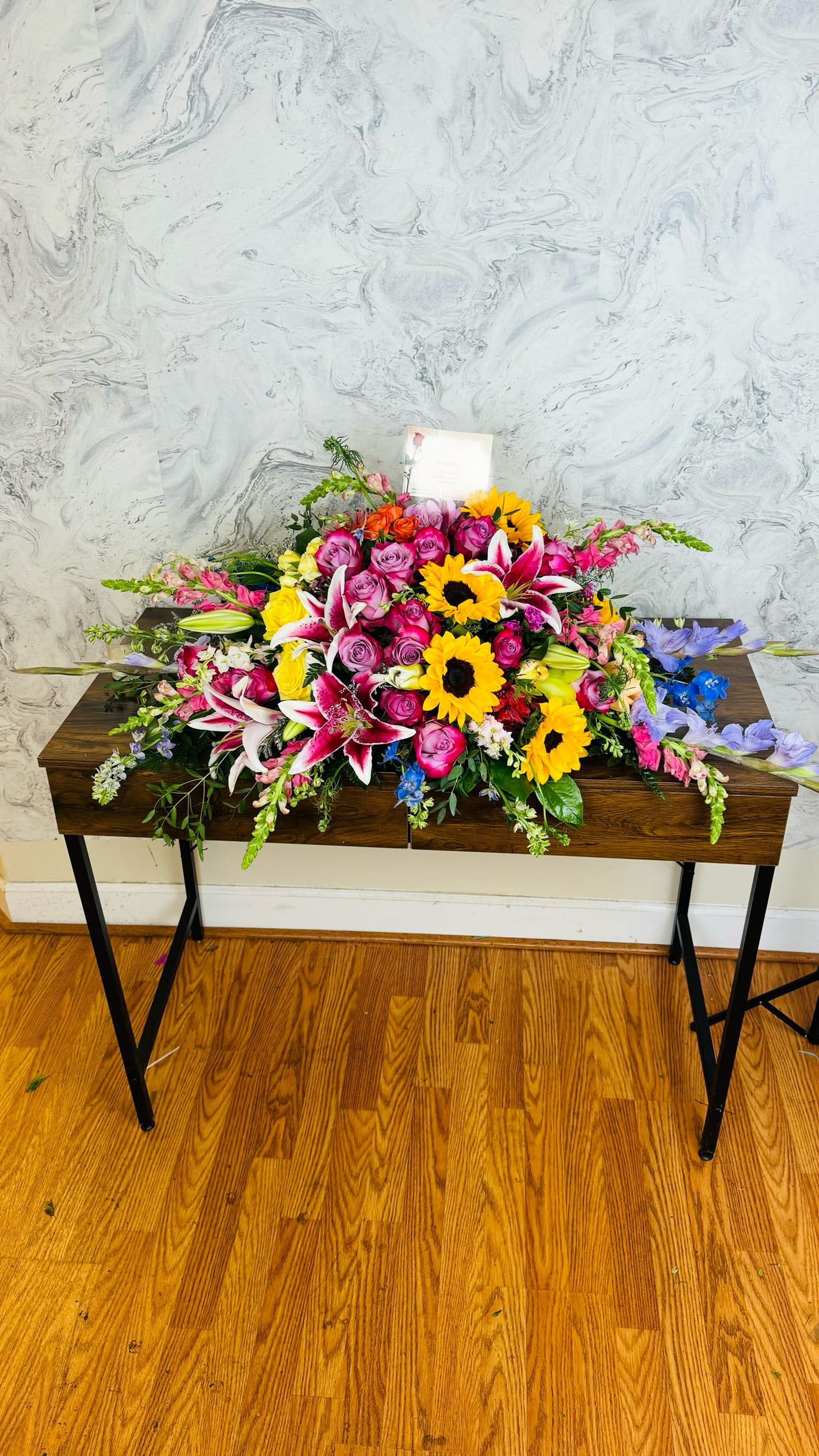 Large mixed flower arrangement with roses, lilies, and sunflowers on a table