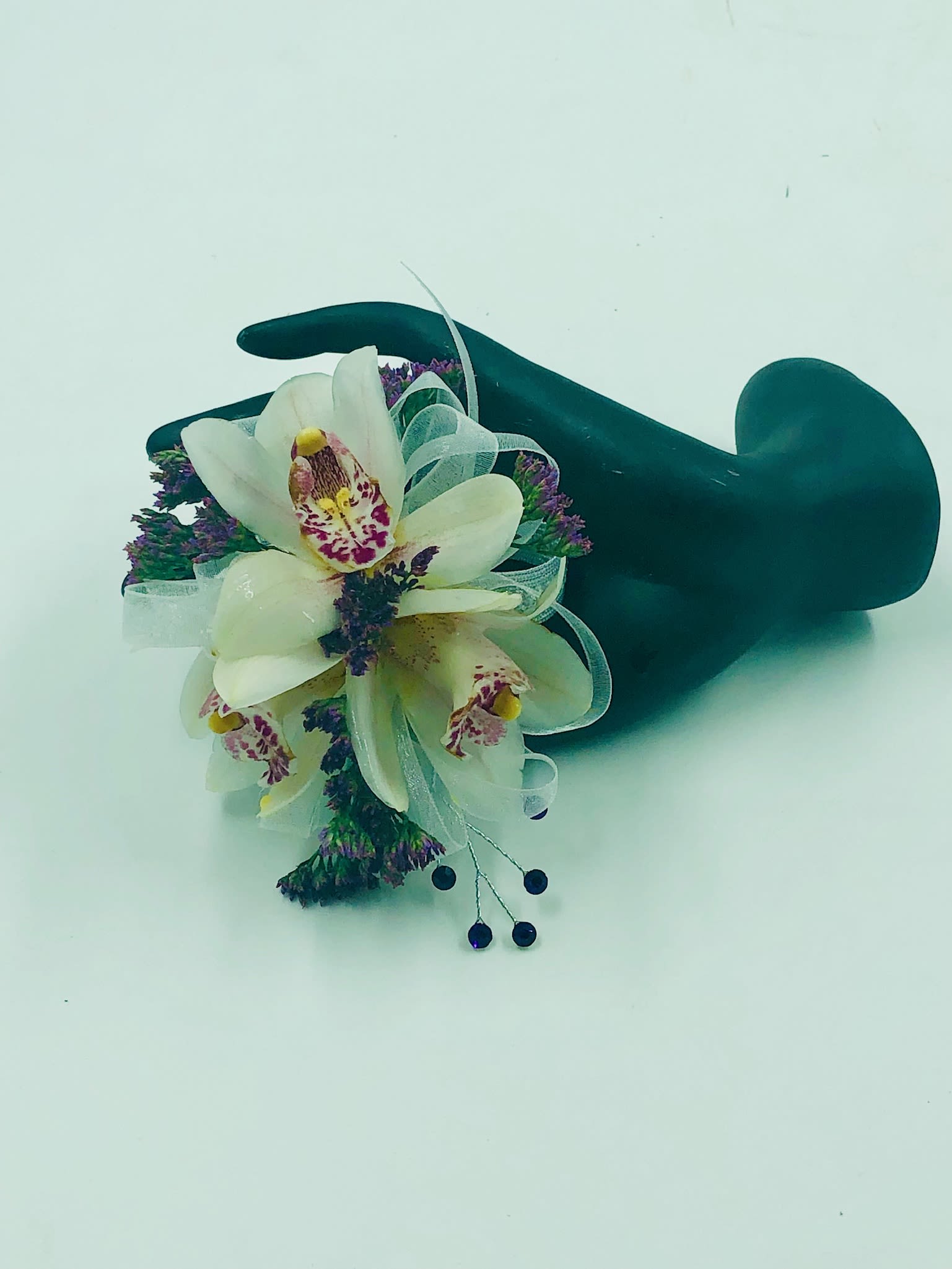 White orchid corsage with purple accents on a dark wristlet