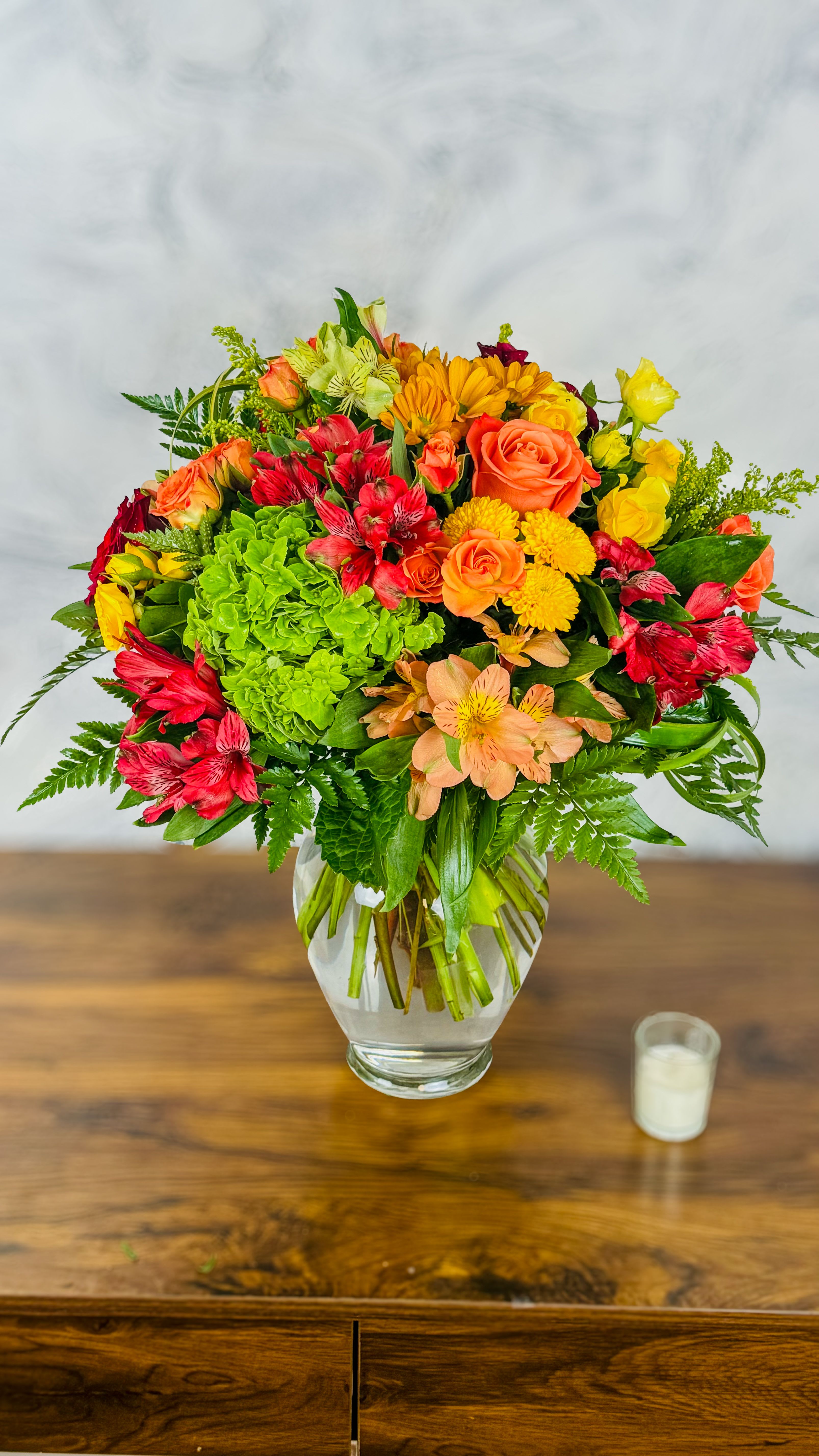 Mixed bouquet of roses, alstroemeria, and chrysanthemums in a glass vase