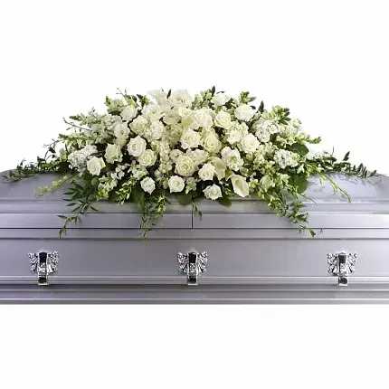 White floral casket spray on a silver casket