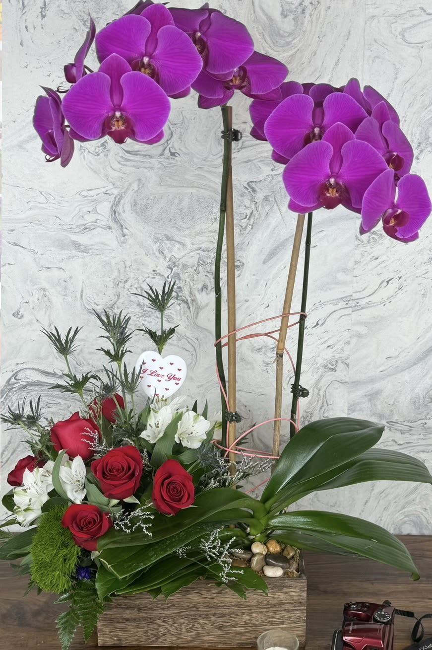 Purple orchids and red roses in a wooden box with a heart pick