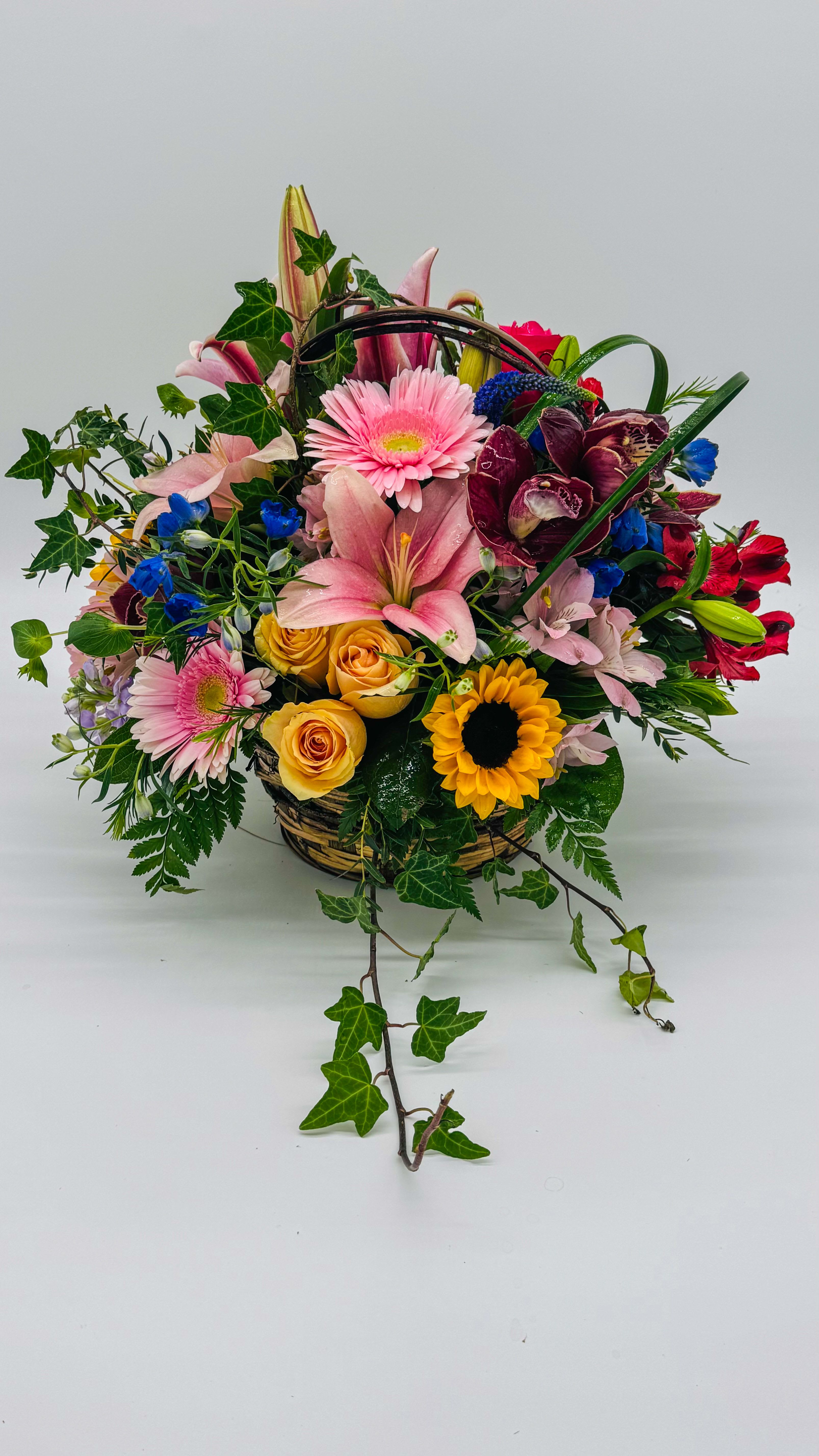 Mixed flower basket with pink lilies, roses, and sunflowers