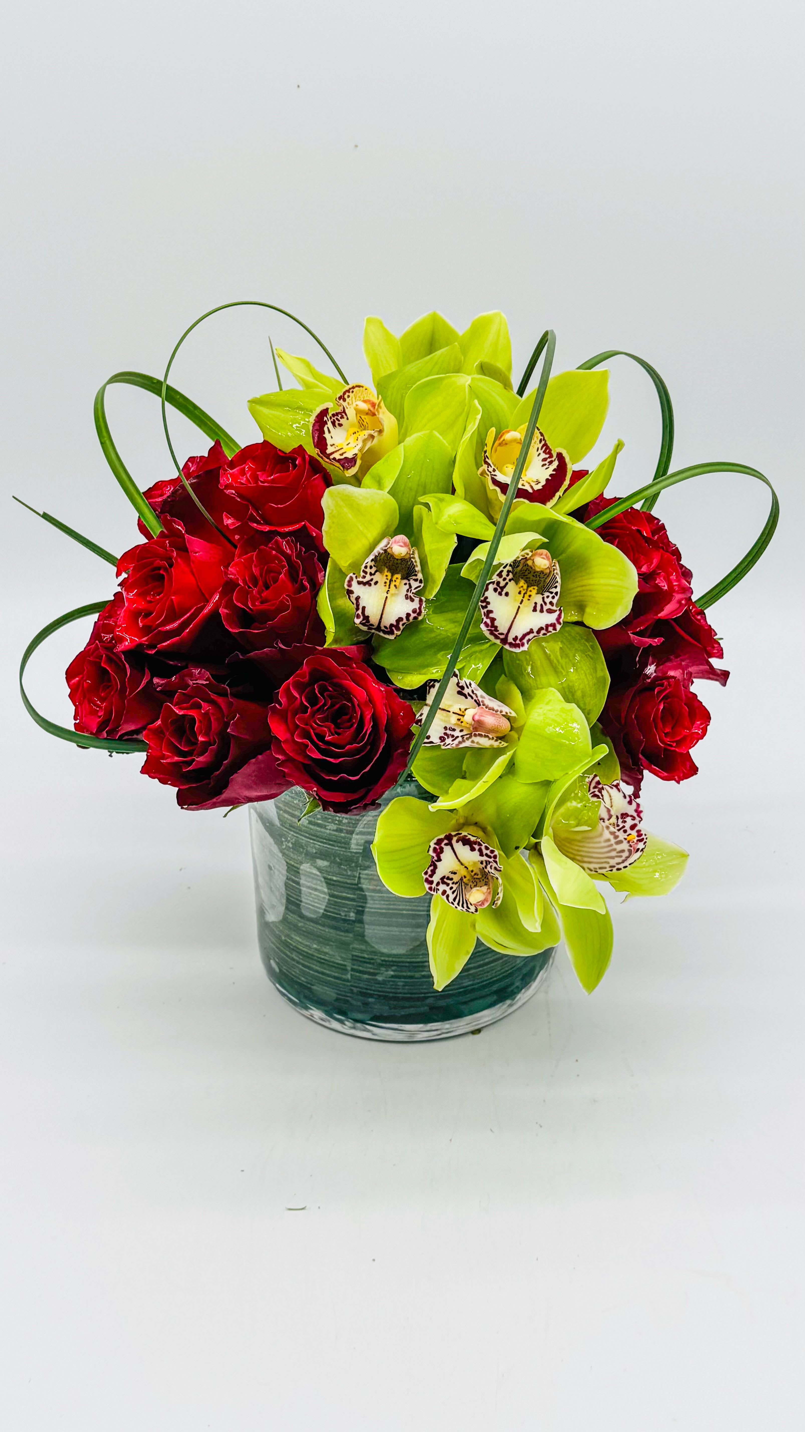 Red roses and green orchids in a glass vase