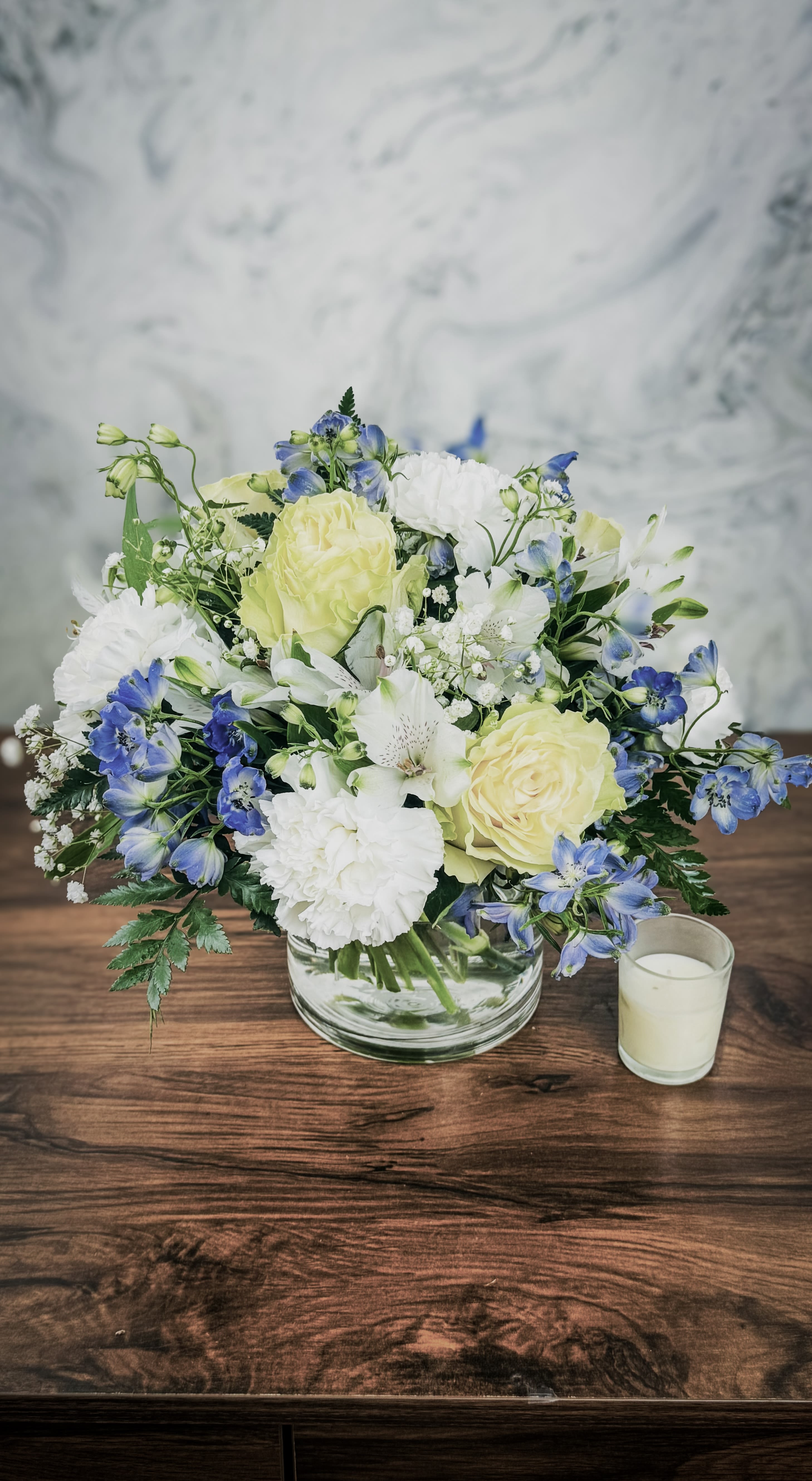 Bouquet of pale yellow and white flowers in a clear glass bowl vase