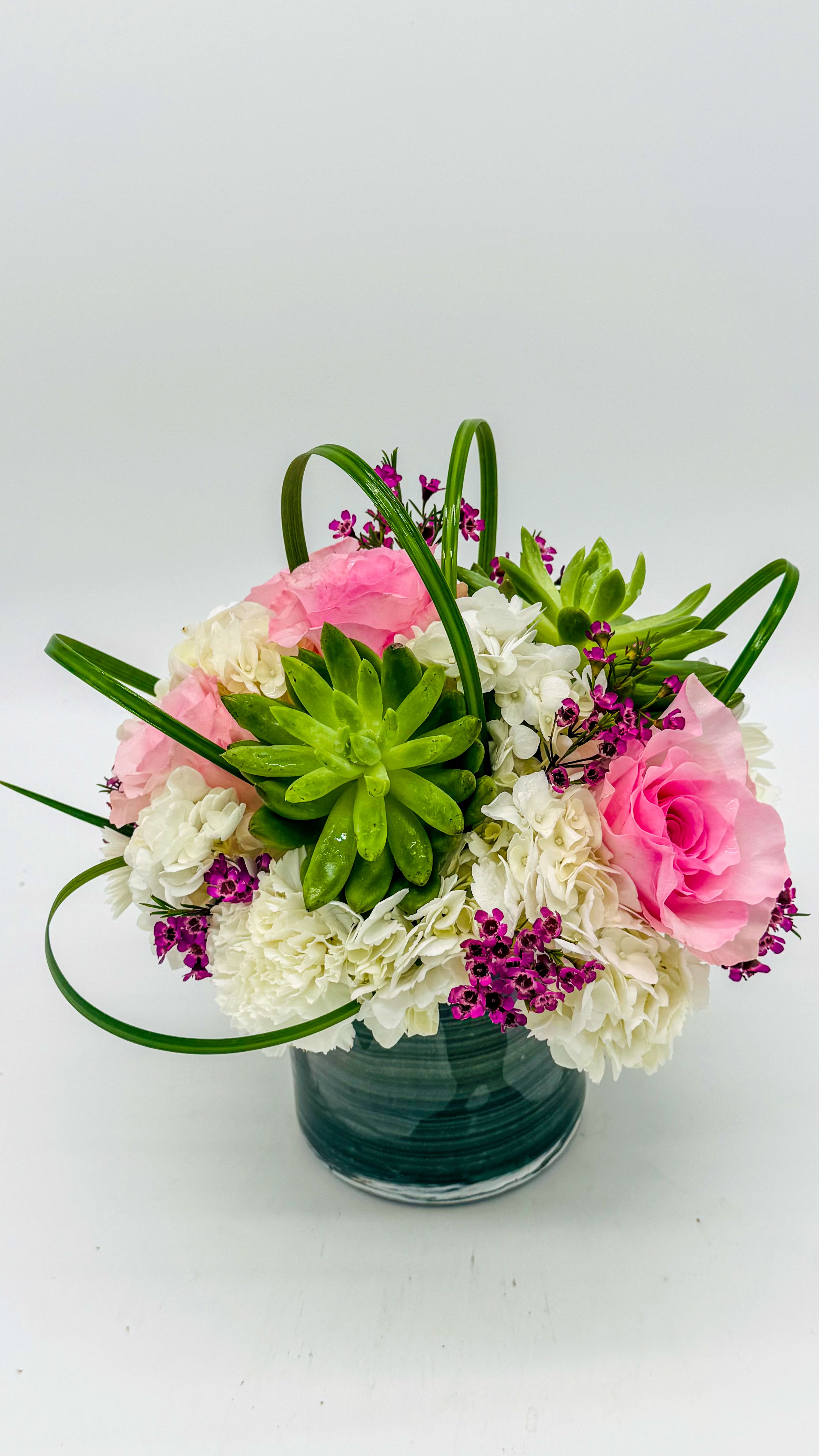 Pink and white flowers with a green succulent in a glass vase