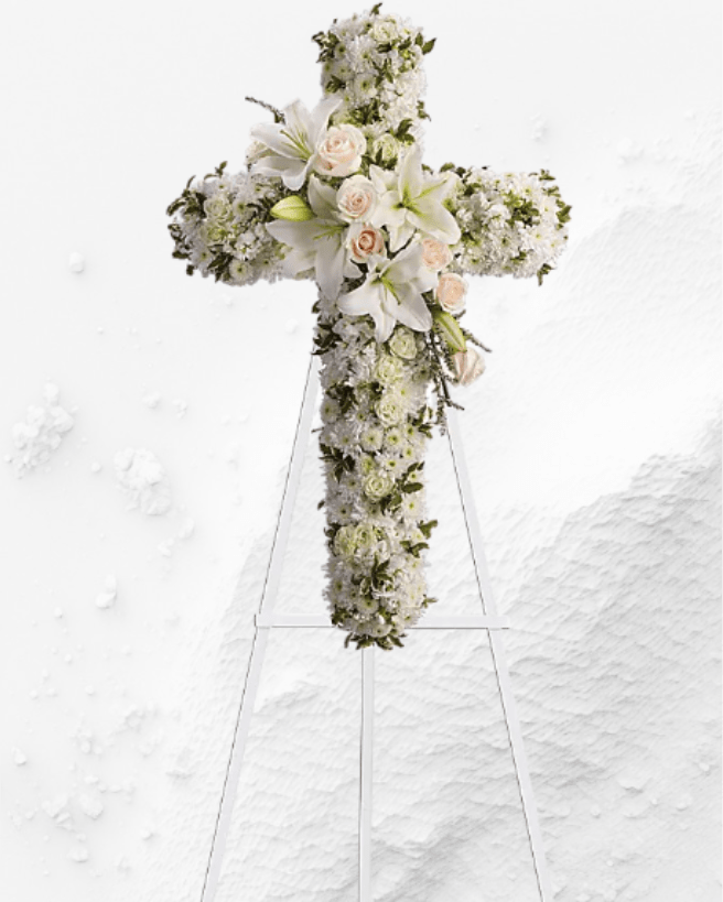 White floral cross on a stand with lilies and roses