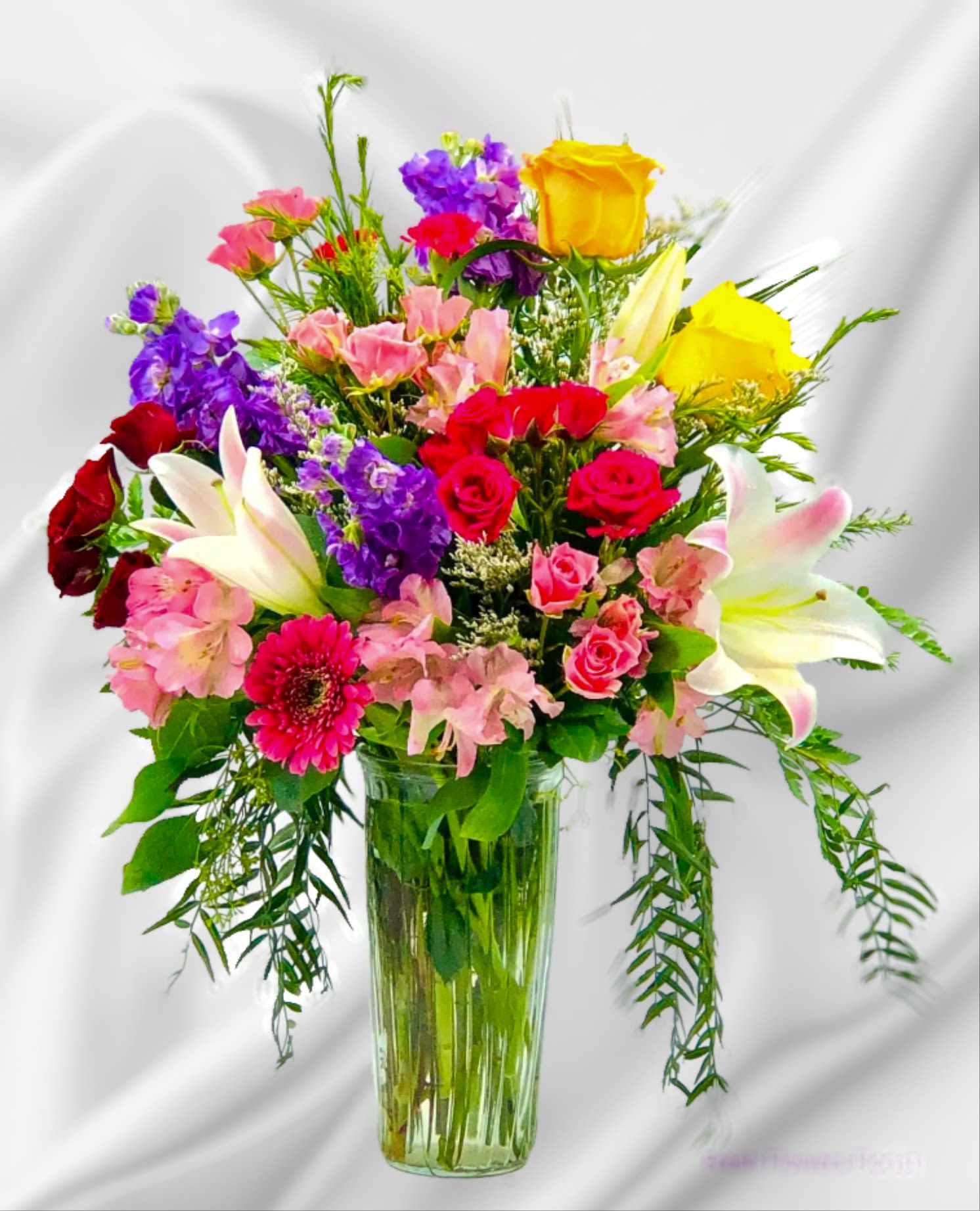 Mixed bouquet of roses, lilies, and pink flowers in a glass vase