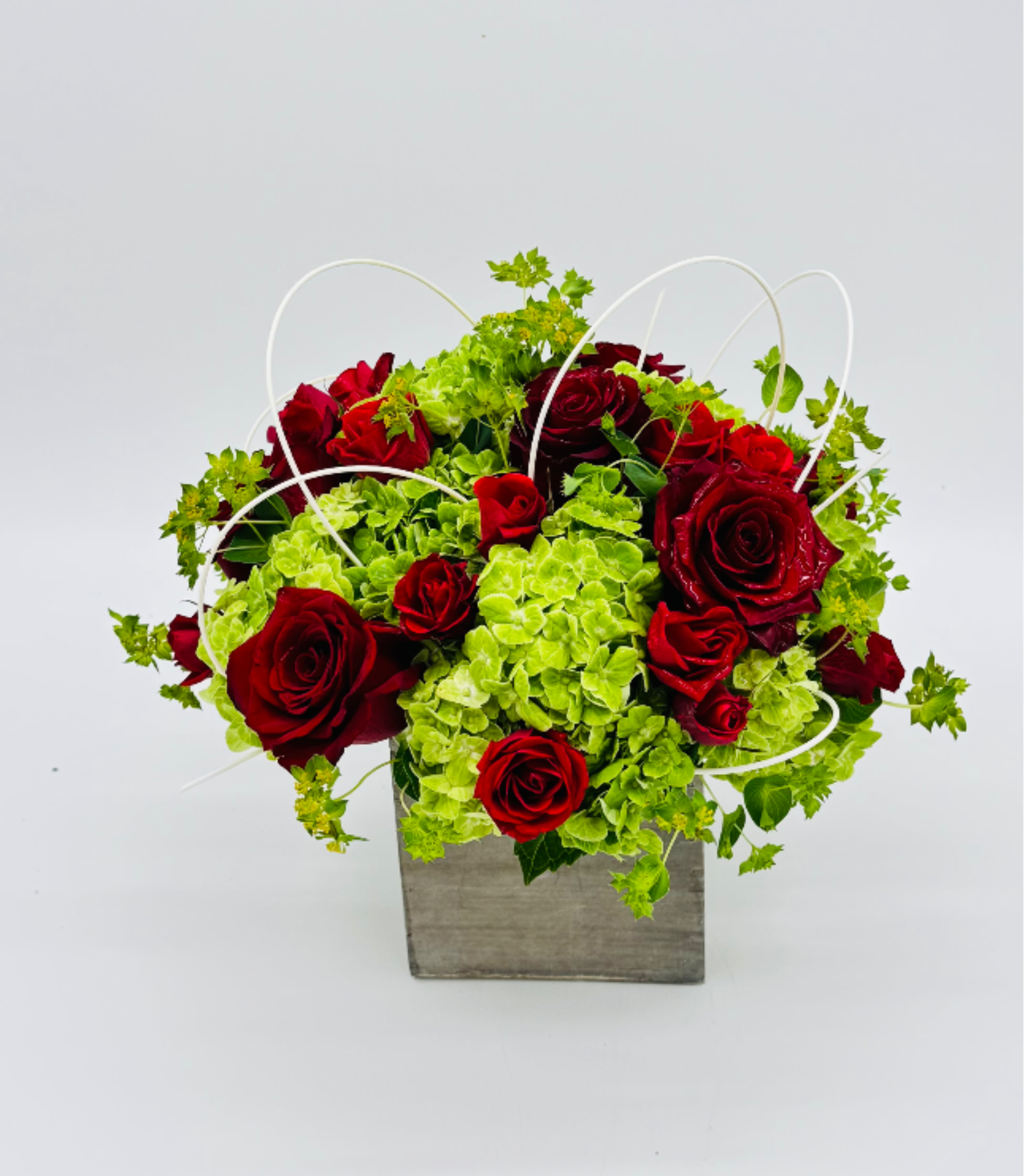 Red roses and green hydrangeas in a square gray container