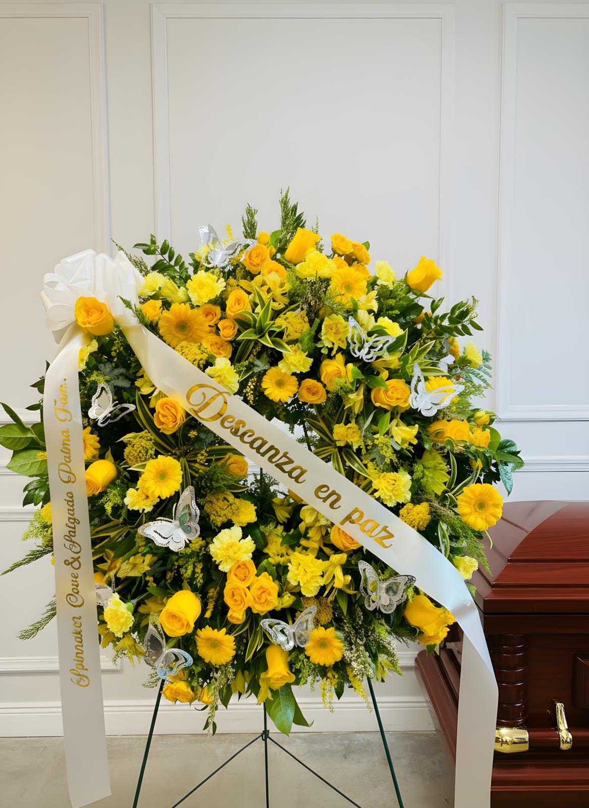 Yellow floral funeral wreath with white ribbon and butterfly accents
