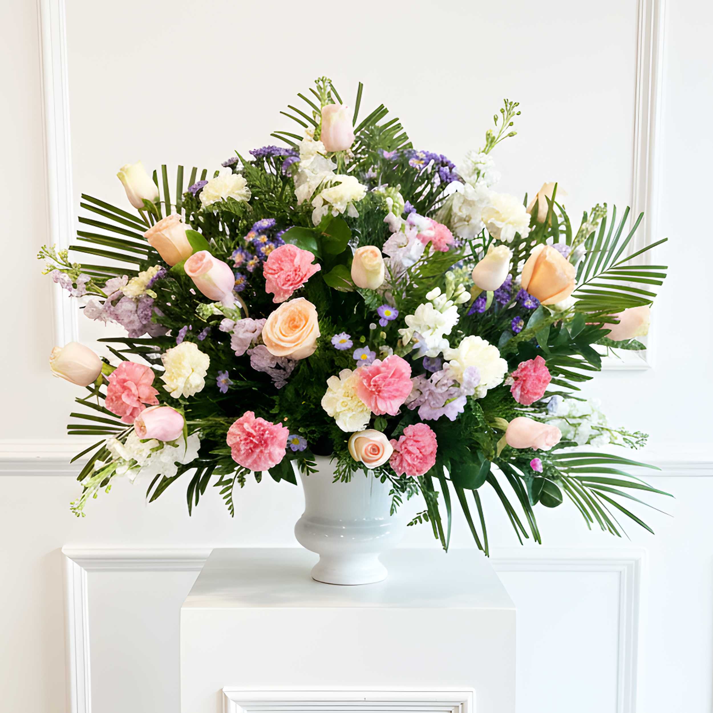 Large mixed flower arrangement in a white urn vase