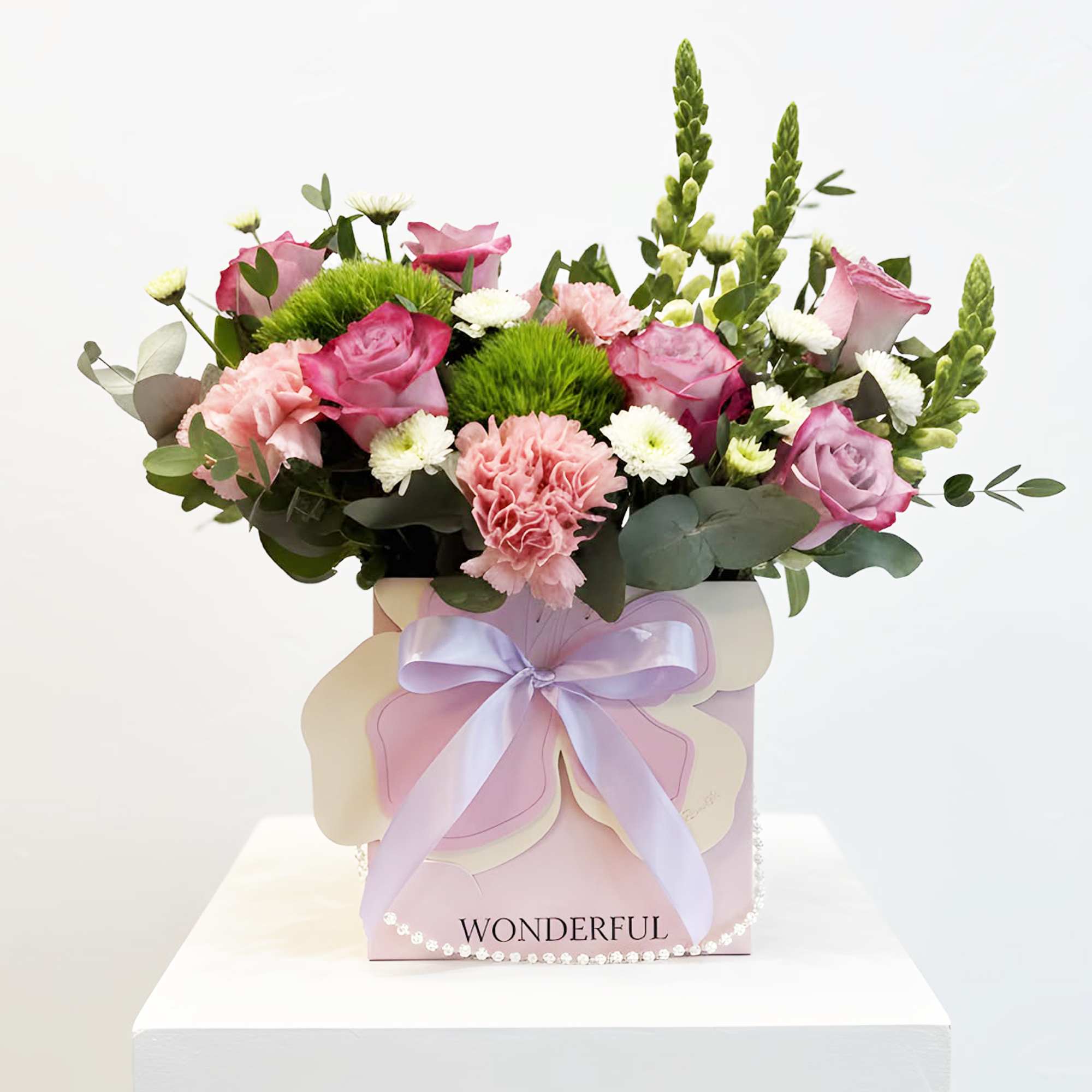 Pink roses and carnations in a pastel gift box with a lavender ribbon