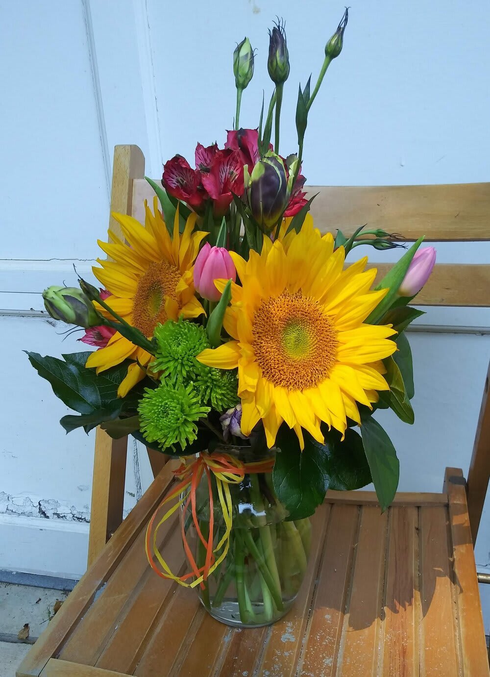 Bouquet of sunflowers, pink tulips, and red alstroemeria in a glass vase